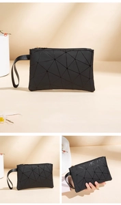 Macro details of black geometric puzzle clutch with matte finish and secure wrist strap