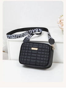 Macro shot of black quilted faux leather crossbody bag with golden metal hardware detail