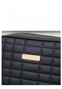 Detail shot of black quilted faux leather fabric with polished gold metal plaque