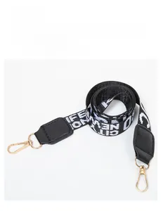 Close-up of wide woven shoulder strap with black faux leather and gold metal rotating hooks