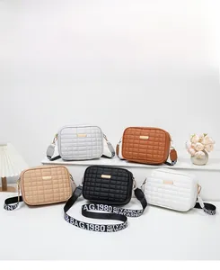 Detailed arrangement of five quilted square crossbody bags in neutral tones with strap