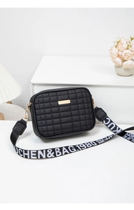 Close-up of quilted black camera bag with gold hardware and wide lettered strap
