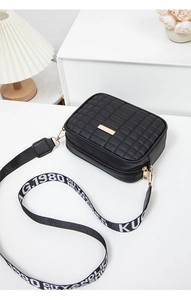 Detail of black quilted camera bag with gold hardware and logo webbing strap