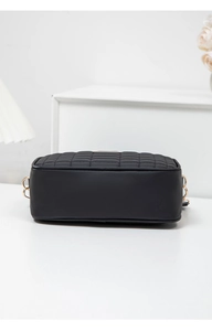 Side view of black quilted crossbody bag showing fine grid texture and gold hardware