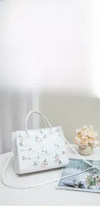 Detail of white handbag with pink flower embroidery on a stylish textured setting