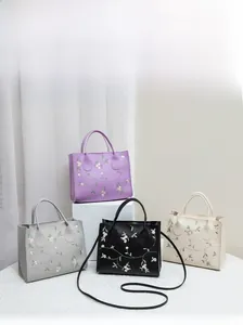 Detail of floral embroidery on PU leather tote bags in purple, grey, black and beige