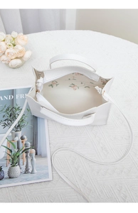 Top view of the white handbag showing the elegant pink floral lining and inner space