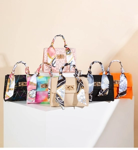 Detail view of assorted mini crossbody bags with silk scarf handles and metal turn-locks