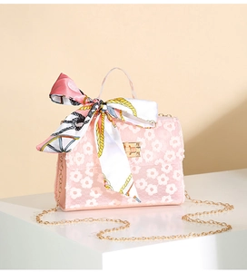 Detailed shot of pink floral lace handbag with silk scarf bow and gold lock buckle