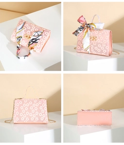 Detail view of pink floral handbag featuring daisy embroidery, silk scarf and gold chain