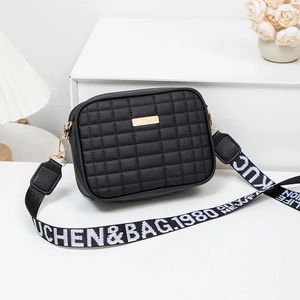 Quilted black crossbody camera bag with wide woven strap and gold metal hardware