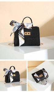 Detail of black textured crossbody bag featuring gold twist lock and printed silk scarf