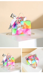 Detail view of colorful tie-dye handbag featuring a gold lock and silk scarf handle