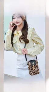 Close-up of leopard print phone bag with a gold crown charm and black leather tassel
