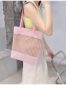 Model carrying a pink hollow woven tote bag with leather handles in a lifestyle setting