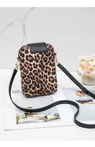 Detail of leopard print crossbody phone bag with gold hardware and slim strap on marble top