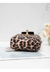 Close-up of leopard print crossbody bag with gold chain strap on white marble table