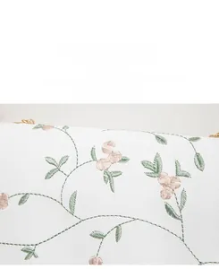 Détail de la broderie florale sur un sac bandoulière blanc en cuir texturé de qualité