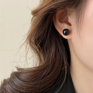 Elegant black spherical stud earrings shown on model for visual scale and minimalist style