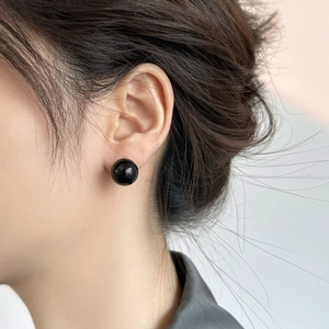 Close-up of elegant black pearl stud earring worn by model with high gloss finish