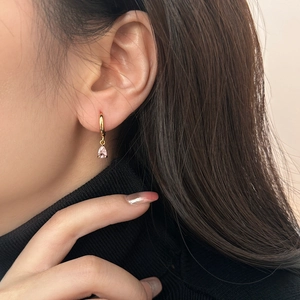 Elegant gold drop earrings with pink pear-cut zircon crystals worn by a model