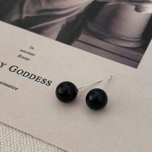 Macro view of black pearl stud earrings with 925 silver hallmarks and vintage texture