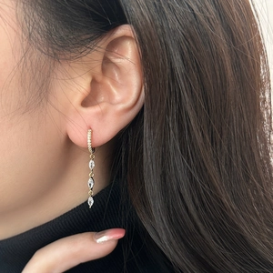 Close-up of elegant gold long tassel earrings with marquise-cut marquise stones on model