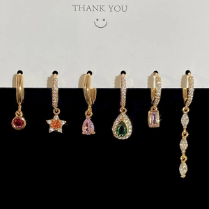 Detail of six gold hoop earrings with colorful zircon stones in various shapes and sizes