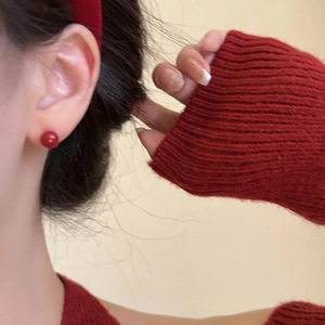 Detalle de aretes de perla roja brillante con una diadema a juego para mujer