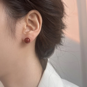 Primer plano de elegantes pendientes de bola rojos usados para un refinado aspecto festivo