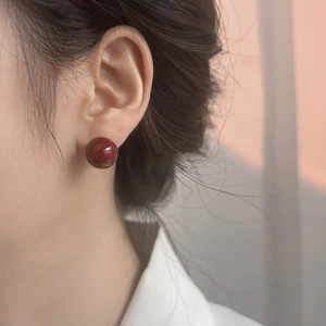 Primer plano de pendientes de bola roja brillante usados en la oreja de una modelo