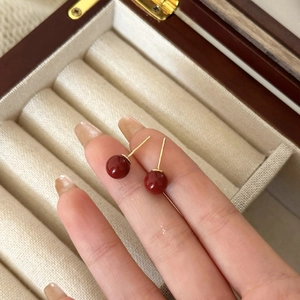 Vista macro de pendientes de perlas rojas minimalistas con pasadores dorados