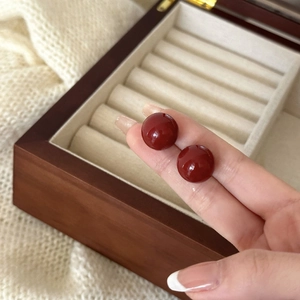 Vista detallada de elegantes pendientes de cuentas rojo oscuro para mostrar tamaño
