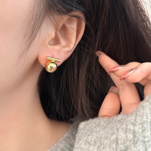 Minimalist gold ball stud earrings shown on model with polished metallic finish