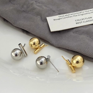 Close-up of gold and silver geometric metal sphere earrings on a textured background