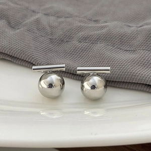 Macro shot of minimalist silver metal ball earrings with a high-polished finish