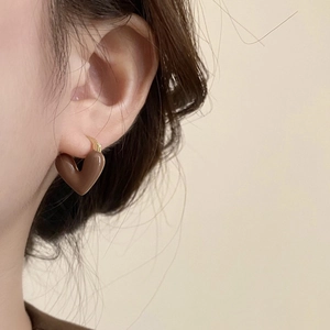 Close-up of caramel heart earrings with gold metal accents on model ear