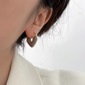 Close-up of mocha brown heart-shaped drop earrings in gold finish on model