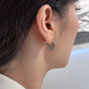 Close-up of a model wearing brown heart-shaped drop earrings with gold metal hooks