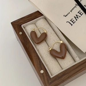 Gros plan de boucles d'oreilles cœur en émail marron dans un coffret à bijoux chic
