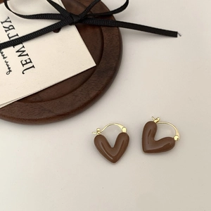 Détail macro de boucles d'oreilles cœur marron chocolat brillant avec crochets dorés