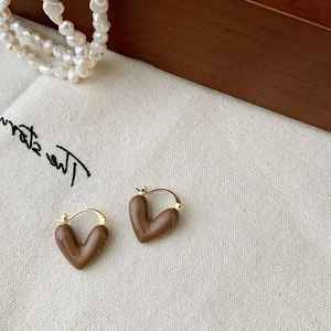 Gros plan de boucles d'oreilles cœur marron sur tissu blanc avec détails de perles