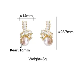 Détail de boucles d'oreilles dorées avec perle de 10mm et design de nœud en zircon