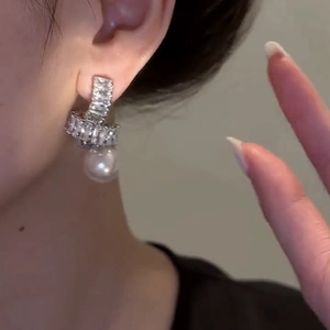 Élégantes boucles d'oreilles nœud en zircon avec perle portées par un mannequin