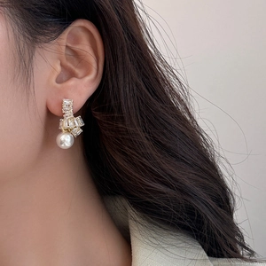 Détail d'une boucle d'oreille pendante avec perle, zircon et finition dorée chic