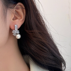 Gros plan de boucles d'oreilles en zircon avec perle blanche portées par un mannequin