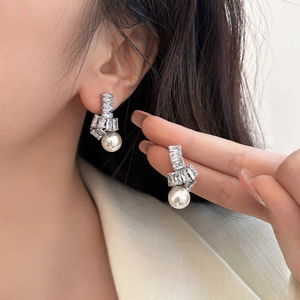 Détail des boucles d'oreilles nœud en zircon avec pendentifs en perles blanches rondes