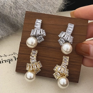 Détail de boucles d'oreilles perles dorées et argentées avec zircon et perles blanches