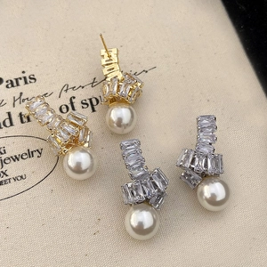 Détail de boucles d'oreilles nœud en zircon doré et argenté avec perles blanches pendantes