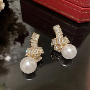 Détail macro de boucles d'oreilles perles dorées avec nud en zircone et fini lustré